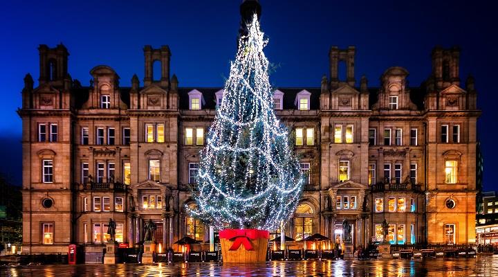 Large Christmas tree lit up on City Square, Leeds at night with building in the background.