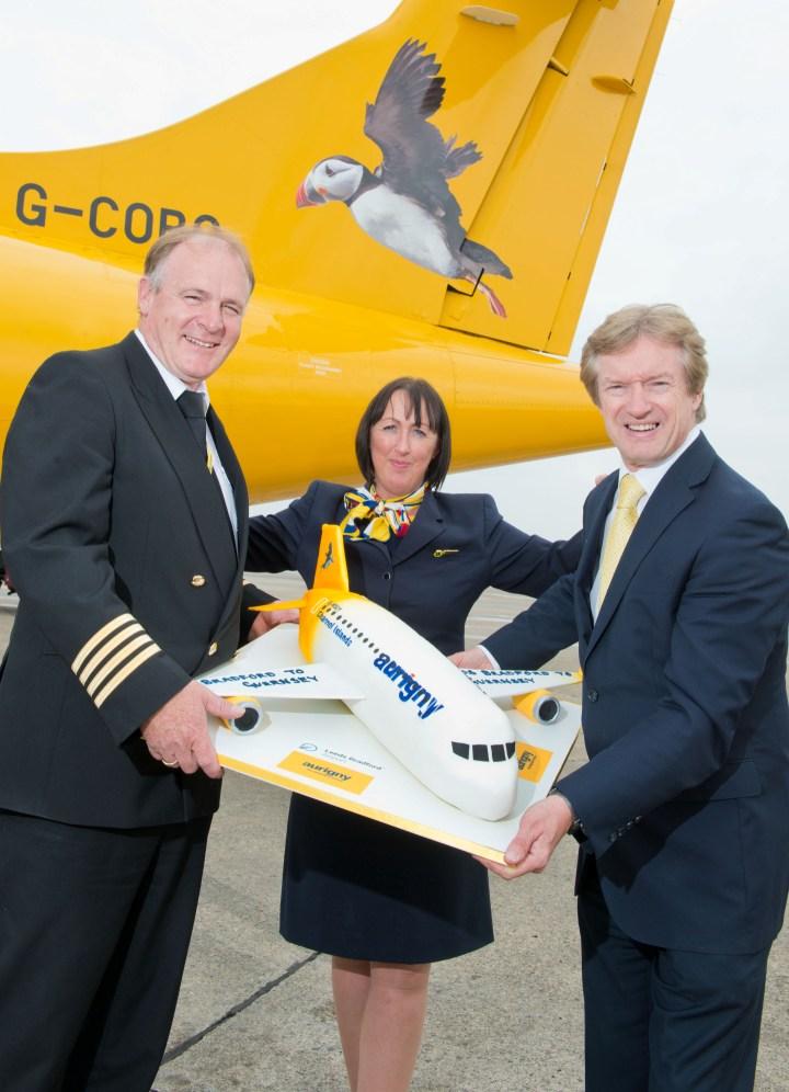 3 people stood in front of a yellow plain holding a model aeroplane