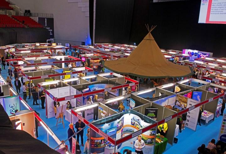 Elevated view of a shell scheme exhibition with a blue carpet and a brown tepee in the middle.