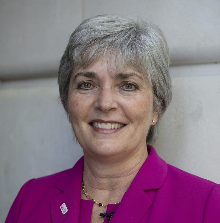 Lady with grey hair wearing a pink jacket smiling