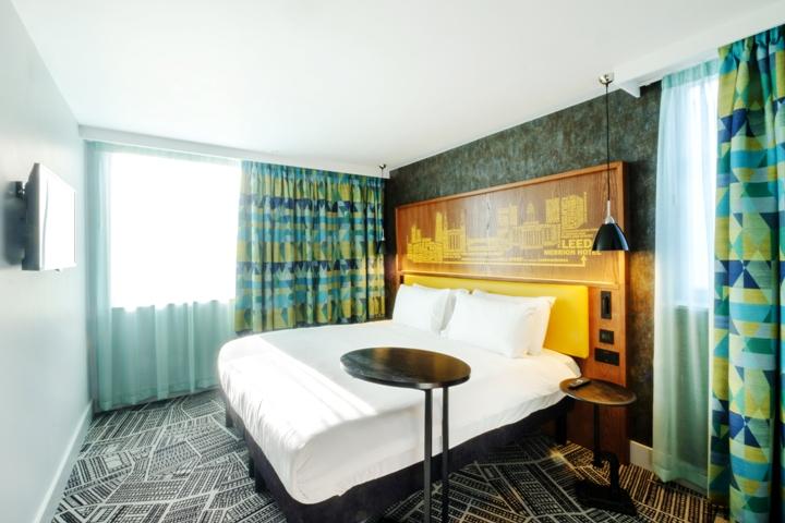 King bedroom at the Ibis styles with white bedding and green and blue patterned curtains.