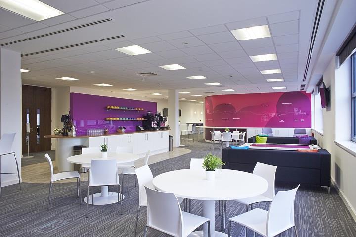 Delegate lounge with white tables and chairs, blur sofas and drinks station with purple splash back.