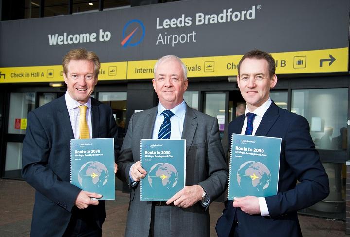 3 men in suits holding proposal dcuments outside the entrance of Leeds Bradford Airport