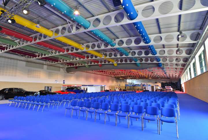 Internal shot of exhibition Hall at Yorkshire Event Centre with blue carpet and rows of blue chairs.